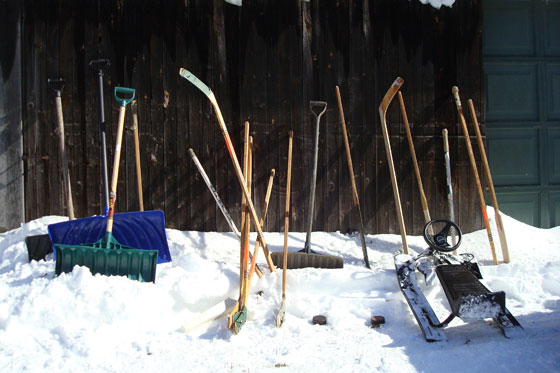 Hockey sticks, snow shovels and a GT snow racer in a snow bank