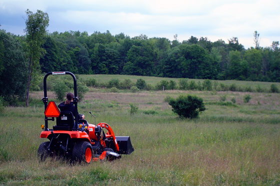 Driving our Kioti CS 2410 tractor across a grassy field