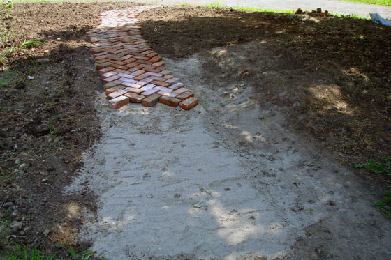Brick pathway laid in a herring bone pattern on a bed of sand