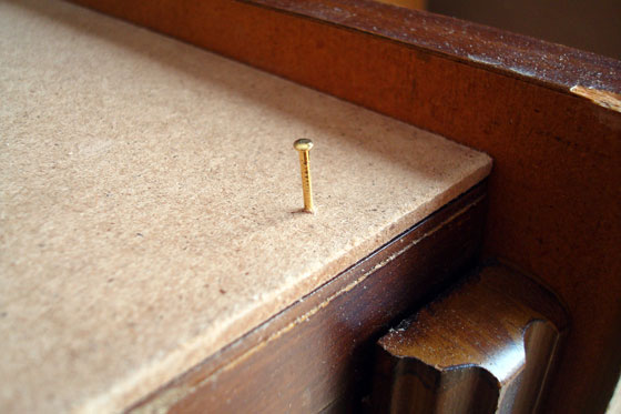 Tacking a board in place with small brass finishing nail