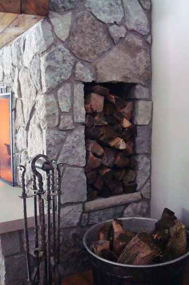 Woodbox in the side of a fieldstone fireplace
