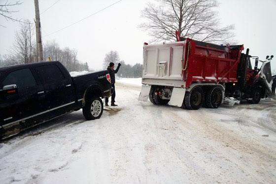 Snowplow pulling a pick-up truck out of the ditch