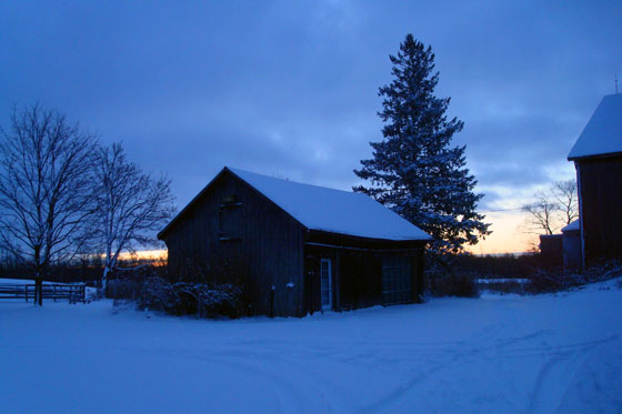 Sun rising over snow covered farm