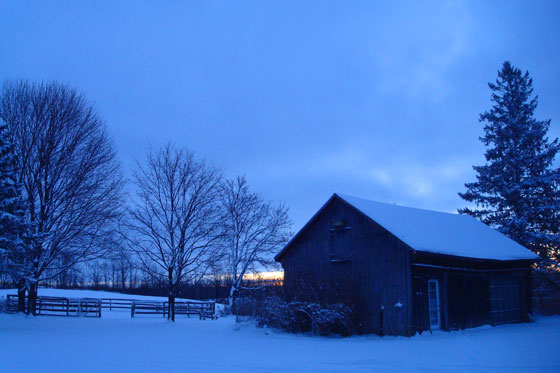 Sun rising over snow covered farm