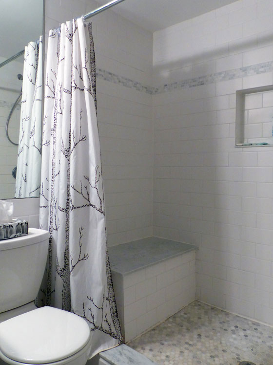 White subway tile shower with a marble seat