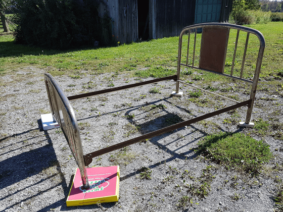 Metal bed frame set up on the driveway for painting