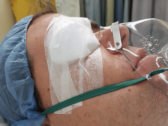 Wearing an eye patch and oxygen mask after surgery
