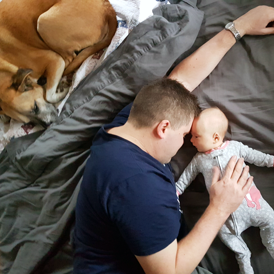 Matt, Ellie and Baxter snuggling on the bed