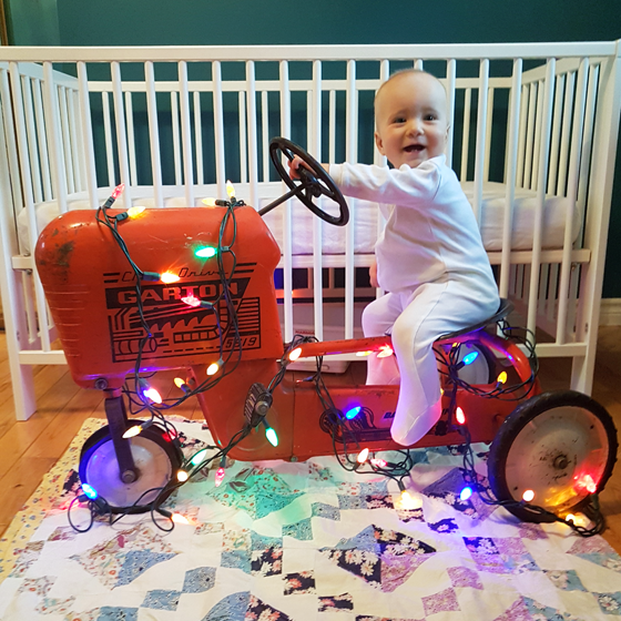 Ellie sitting on her tractor decorated with Christmas lights