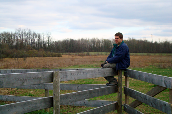 Matt sitting on a fence at the farm