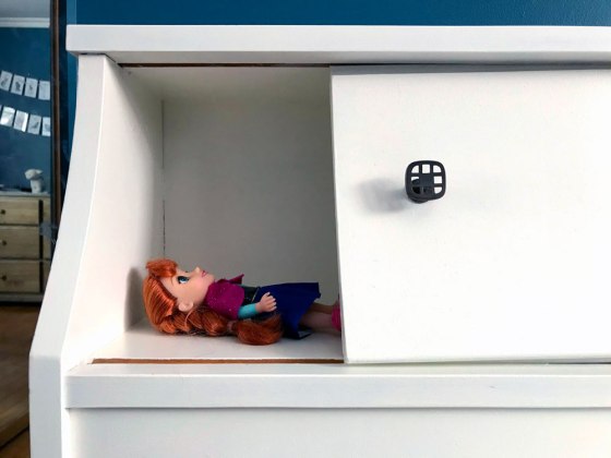 Anna doll lying in a cubby in a bed headboard