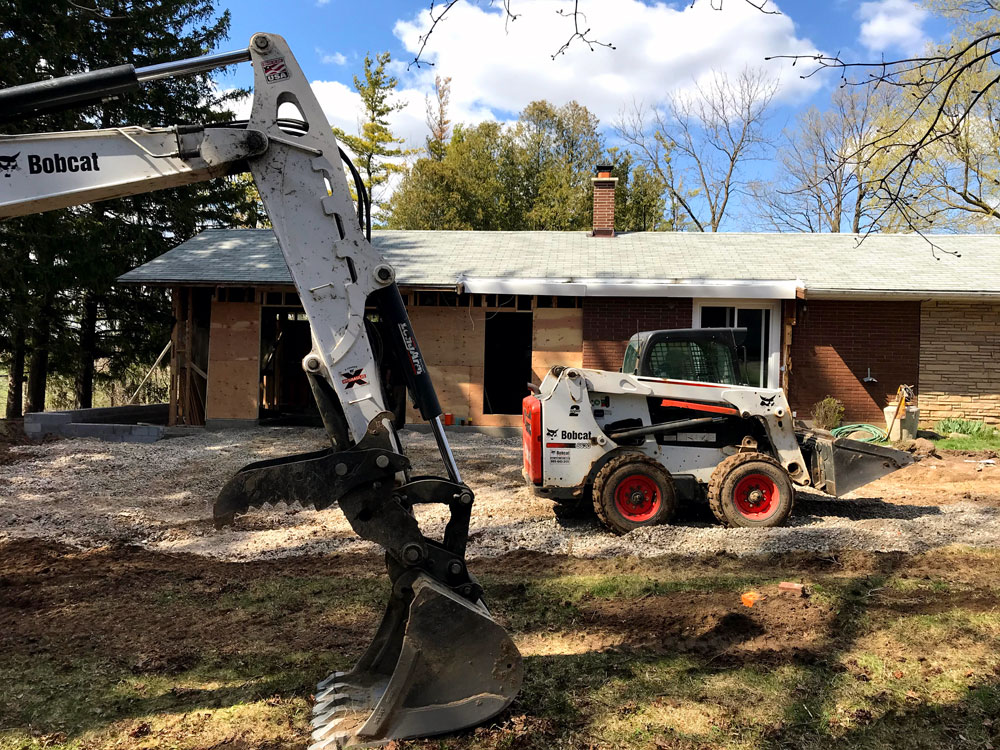 Backhoe and skid steer working on the garage construction