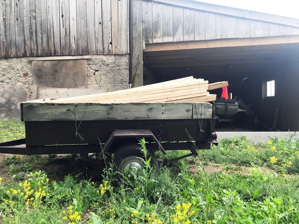 Trailer loaded with lumber parked outside the barn