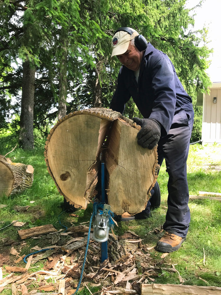 Man splitting a large log in half on a wood splitter